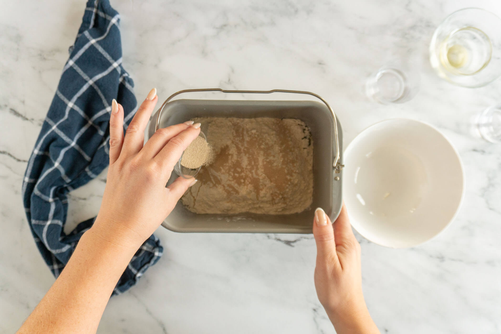 Adding flour and yeast to bread machine pan. 