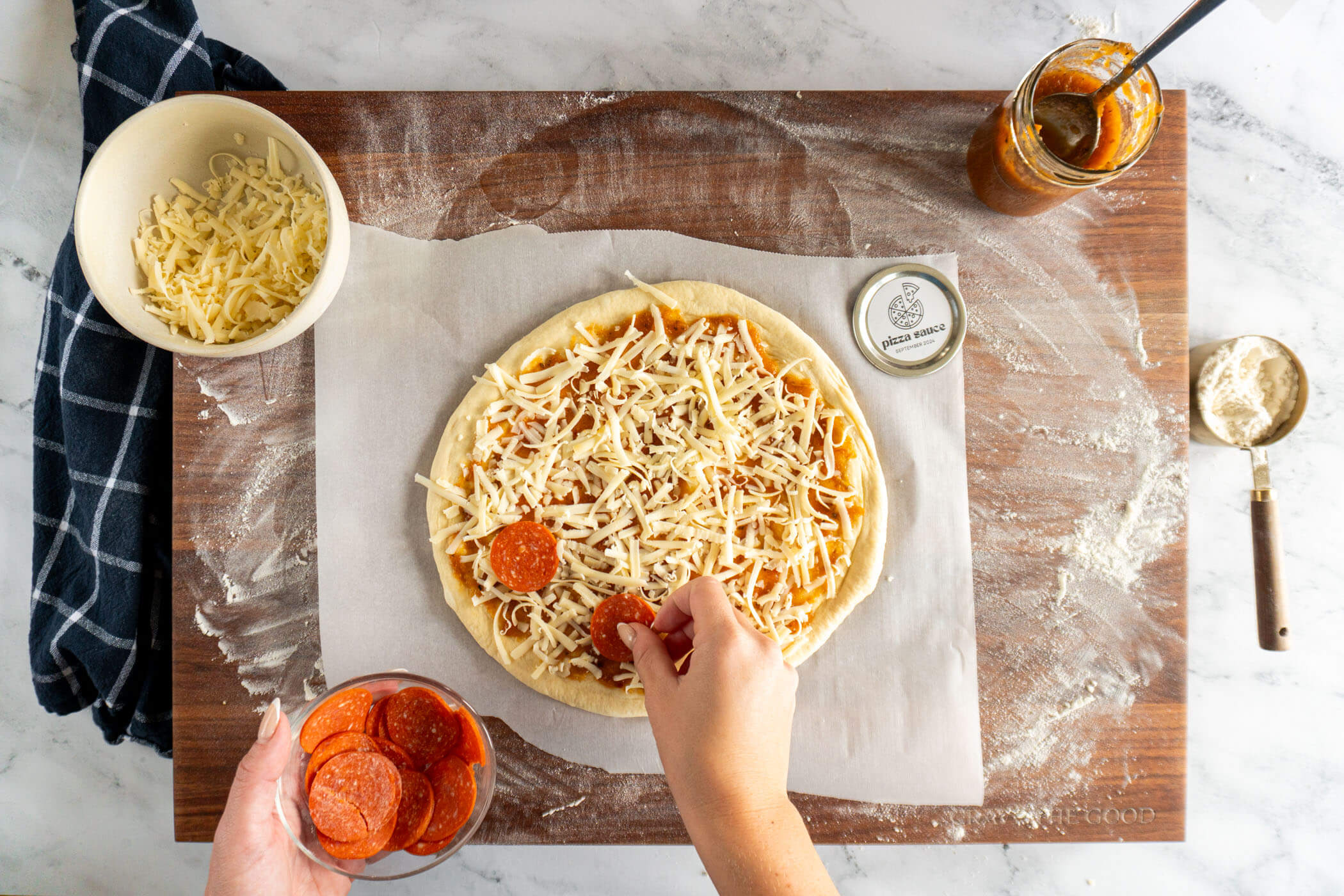 Adding toppings to the pizza. 