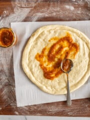 Spreading sauce on homemade bread machine pizza dough.