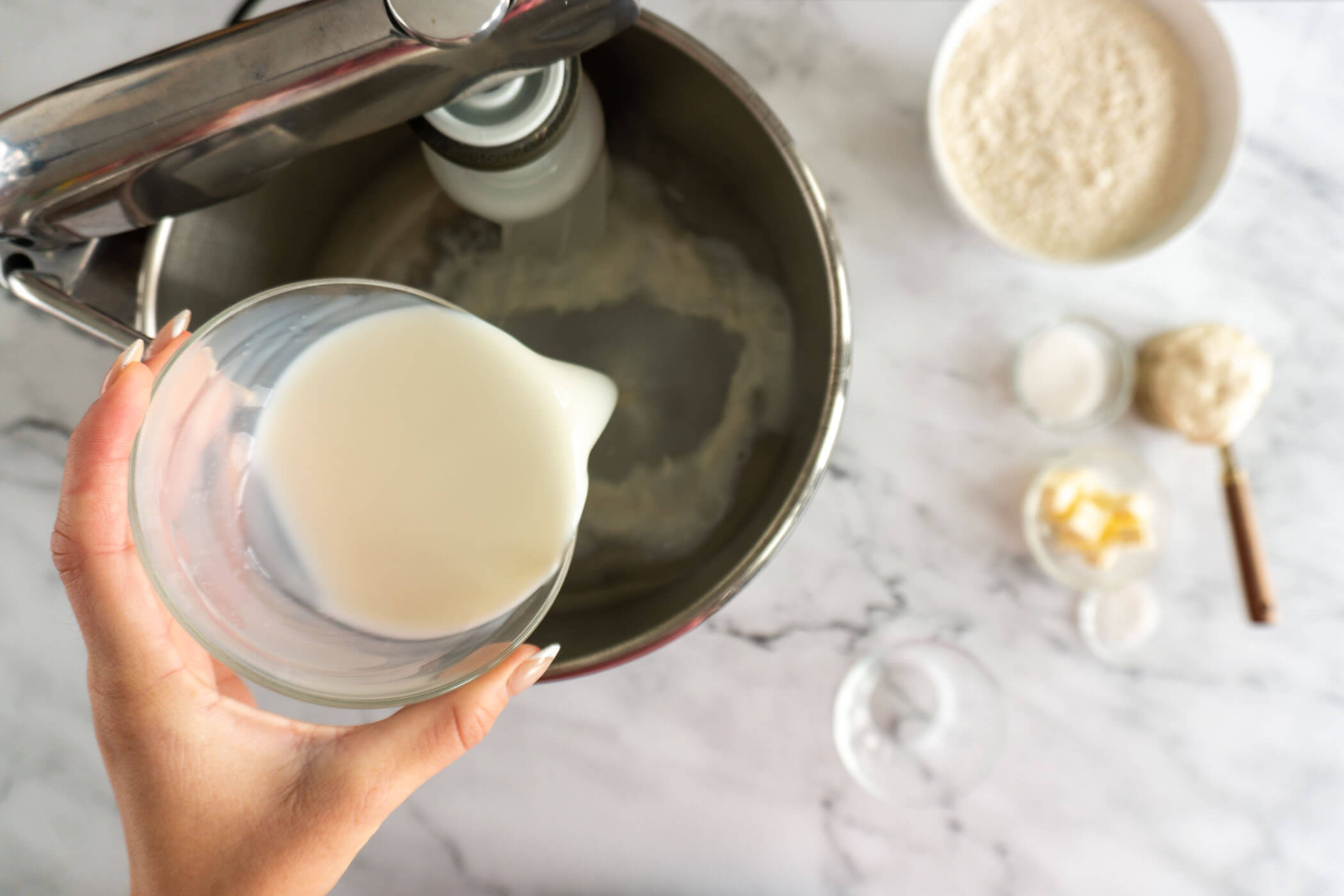 Adding milk to bowl of stand mixer. 