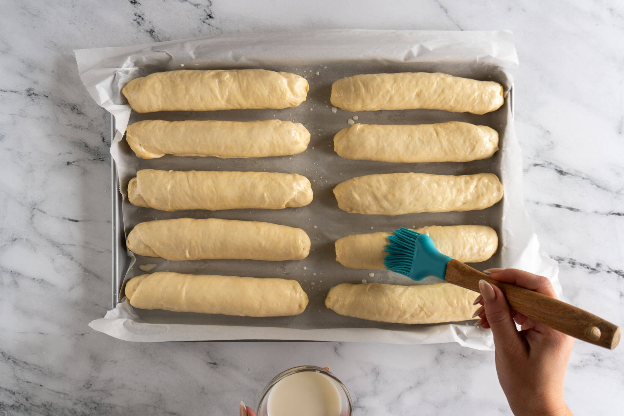 Brushing the raw buns with milk. 