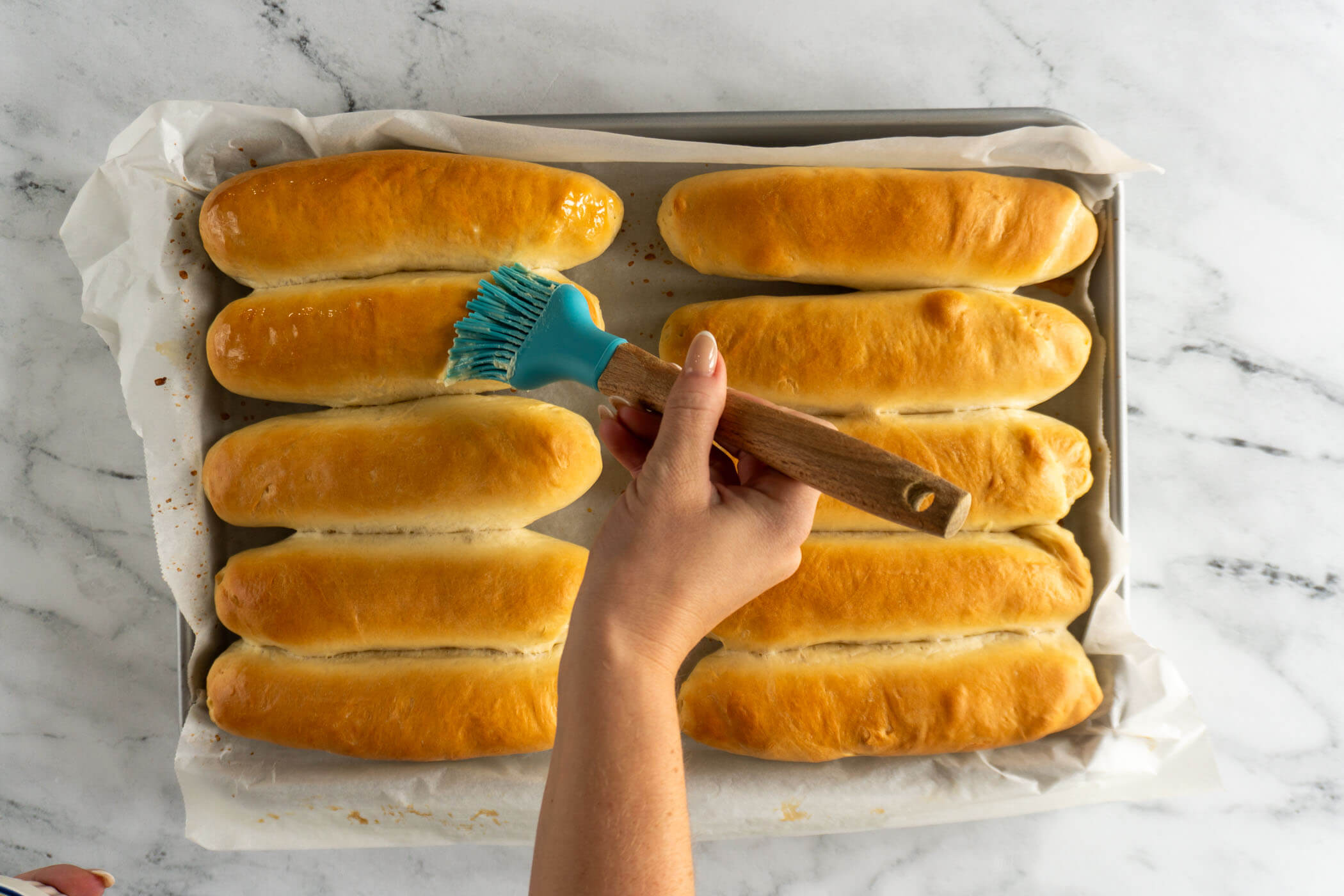 Brushing baked buns with butter. 