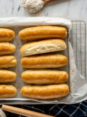 Separated sourdough buns on a baking sheet.