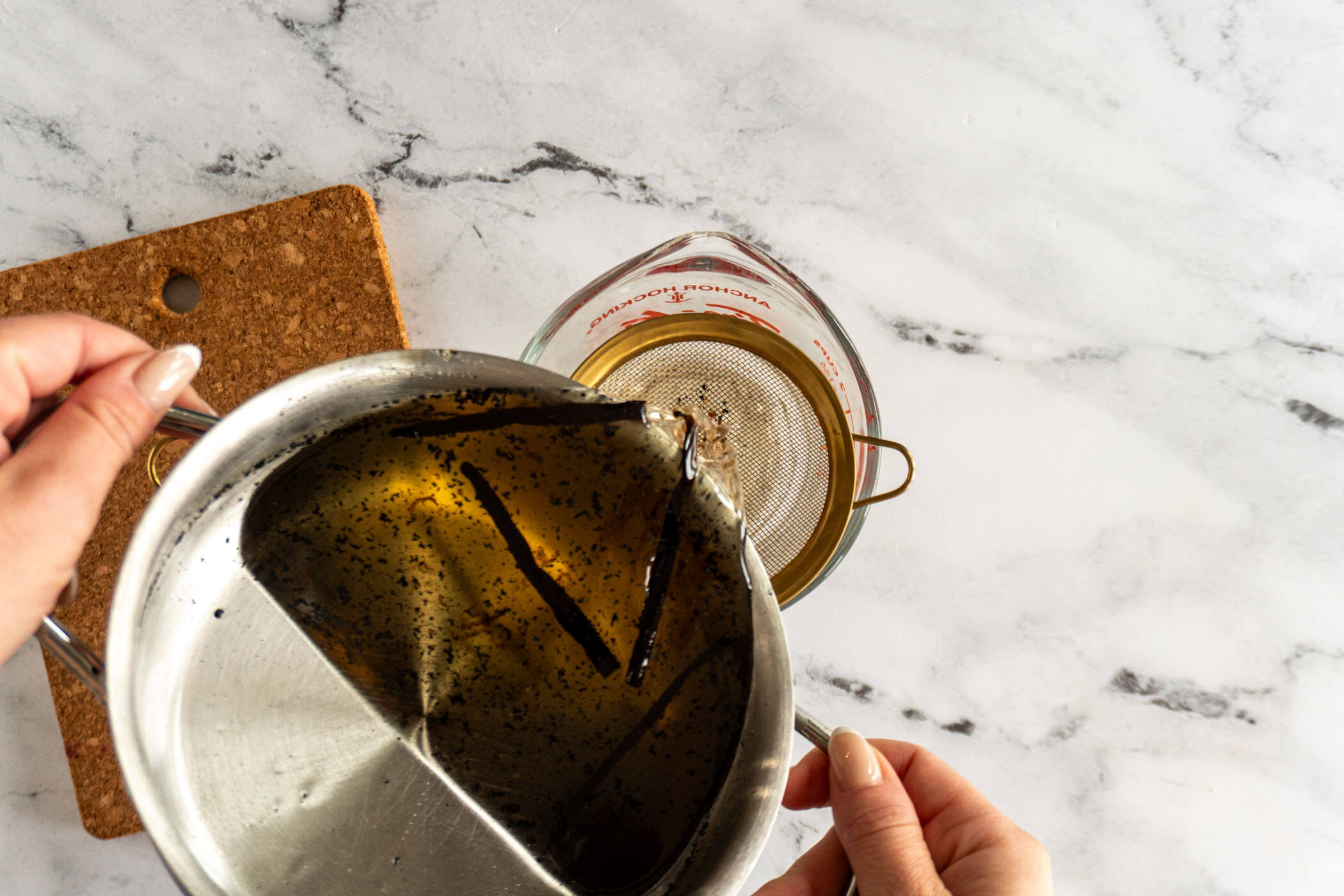 Straining the vanilla latte syrup through a mesh sieve. 