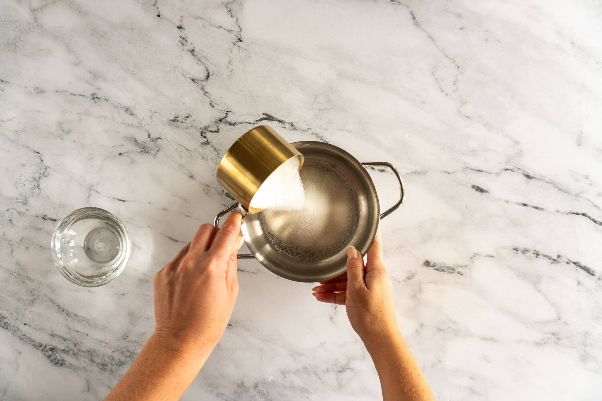 Adding sugar to small sauce pan. 