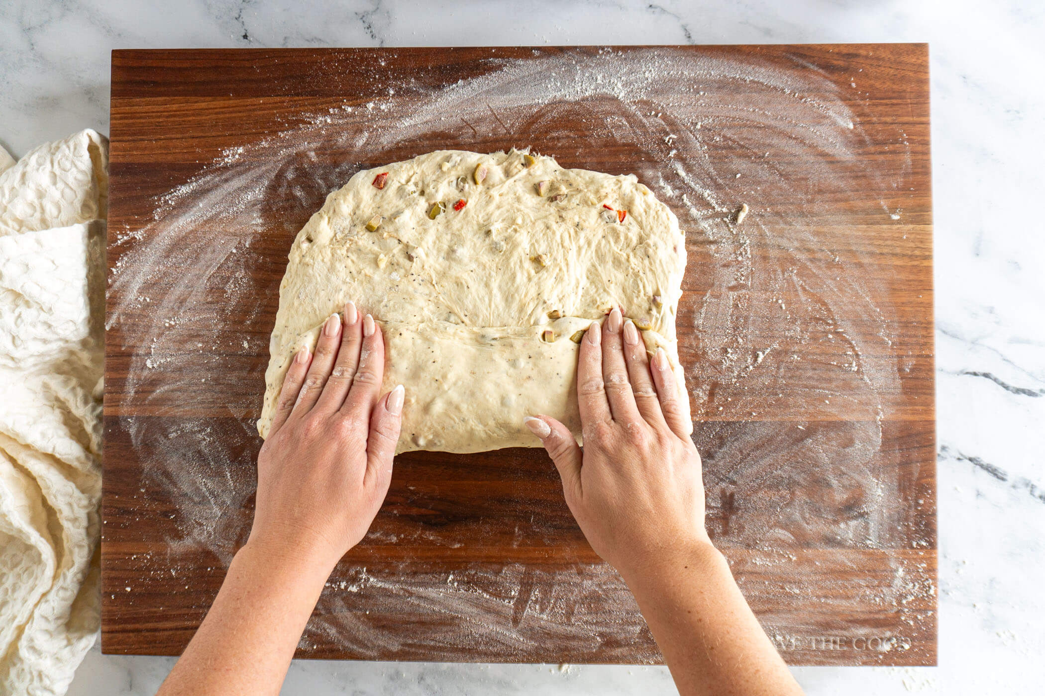 Pressing dough flat, then folding up the bottom third of the dough.