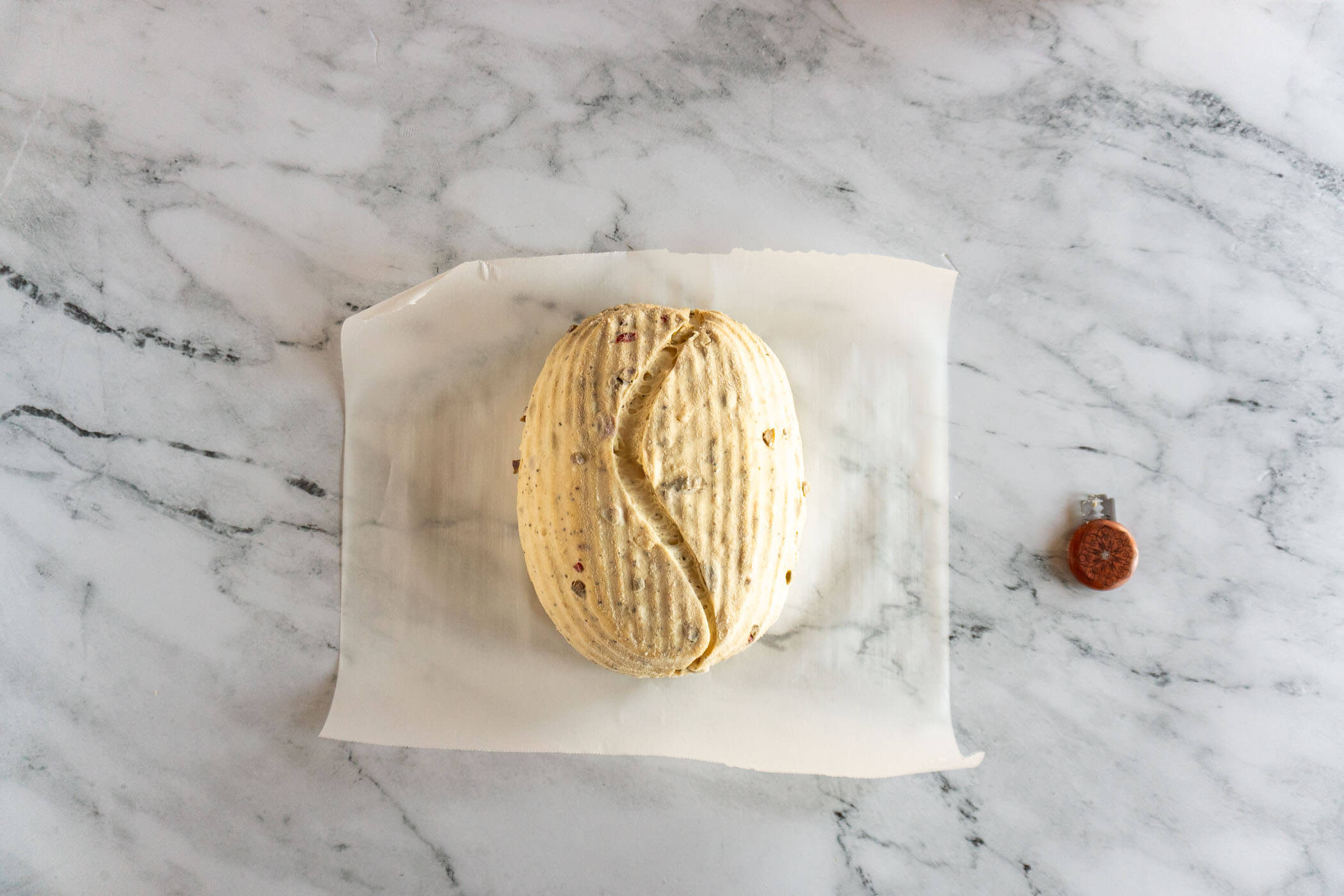 Scored garlic olive sourdough loaf before baking.