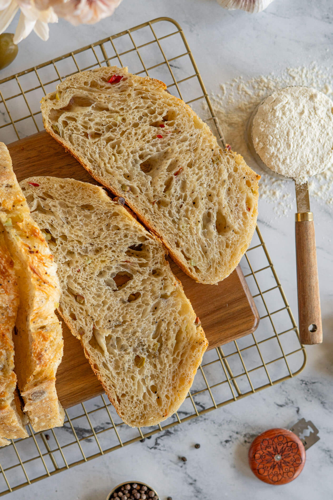 Sliced garlic olive sourdough bread on a wire cooling rack.