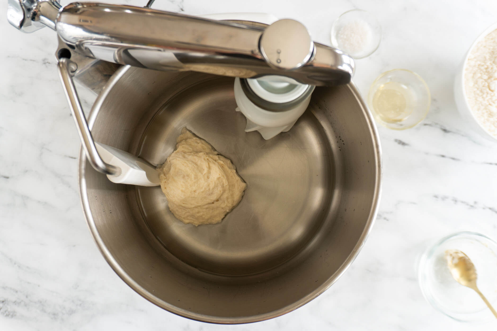 Sourdough starter, water, and honey in the bowl of an Ankarsrum mixer. 