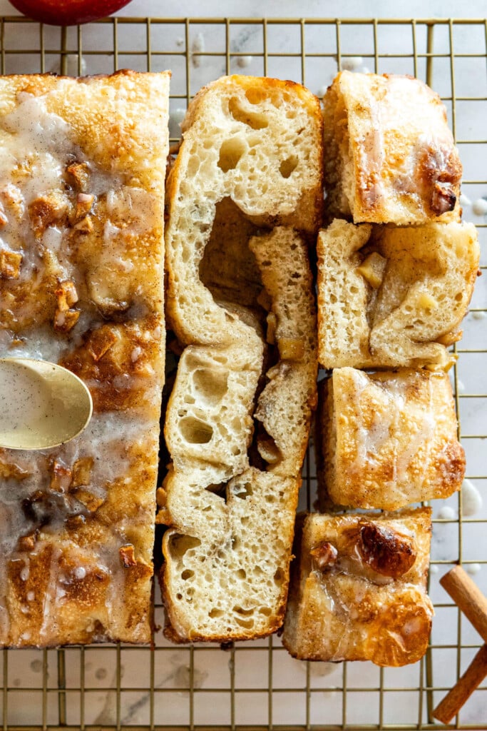 Sliced sourdough apple fritter focaccia with vanilla bean glaze.