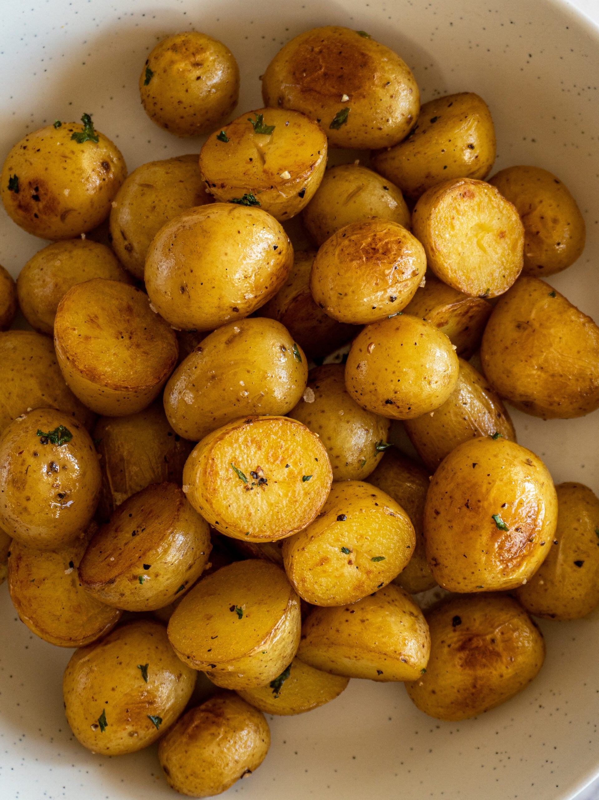 Golden seared sous vide baby potatoes in a bowl, garnished with parsley.